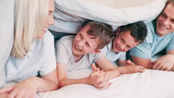 ベッドで子供たちと一緒に話したり 絆を深めたり 一緒に楽しんだりして幸せで笑ったりする親たち スマイル 若い母親と父親は 現代の家庭の寝室で男の子とリラックス — ストック動画