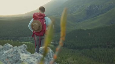 Yürüyüş, ufuktaki dağ manzarası ve uçurumdaki adam, doğa macerasında ve özgürlükte rahatla. Seyahat, kaya tırmanışı, sırt çantalı yürüyüş, yeşil arazi ve doğal ortamdaki motivasyon.