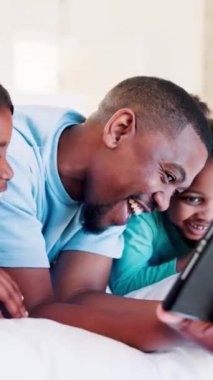 Siyah aile, yatak odasında baba ve çocuklarla oyun ya da uygulamayla oynayan bir tabletle rahatlayın ve sosyal medyayı kullanın. Mutlu baba, çocuklar ve komik video çağrısı, fotoğrafçılık ya da sabahın köründe teknolojiyle çekim.