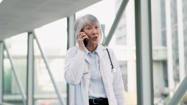 携帯電話で話す廊下を歩いている病院の電話 女性の医師 テクノロジー プロフェッショナル シニアヘルスワーカーが携帯電話でオンラインテレヘルスコンサルテーションを実施 — ストック動画