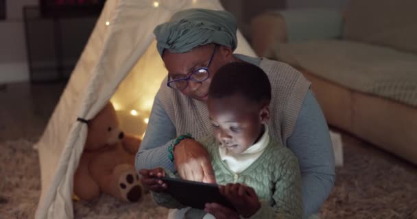 タブレット 家庭で子供と一緒にEラーニングのための映画やビデオを見ています アフリカの女性やおばあちゃんと一緒にラウンジで教育 ストリーミング 電子ブックやストーリー — ストック動画