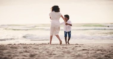 Aile, sahil ve gün batımında deniz ya da okyanus kenarında oğluyla birlikte kumda dans eden bir anne. Enerji, özgürlük ve siyah bir kadın tatilde ya da tatilde çocuğuyla eğleniyor..