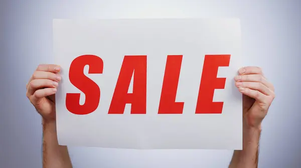 Sale, sign and hands with a poster, promotion and announcement of discount in studio with white background. Retail, shopping and person advertising with news, banner and deal for commercial savings.