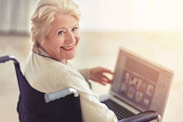Shes a tech-savvy senior. a senior woman using a laptop while sitting in a wheelchair