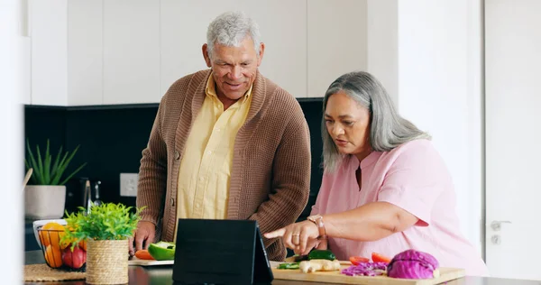 Senior, couple and cooking in kitchen with tablet for dinner, lunch or vegetables with support, help and love. Elderly, man and woman with watching, peace and nutrition for bonding or relationship.