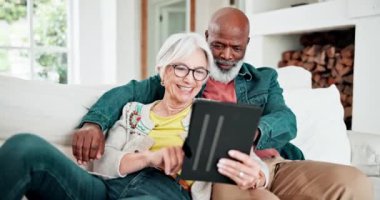 Tabletli yaşlı bir çift, aşkla gülüyor ve rahatlıyor, ırklar arası evlilik ve evde kaynaşma. Sosyal medya mim 'i, dijital uygulama ve mutlu insanlar, oturma odasındaki kanepede oturan yaşlı adam ve kadın