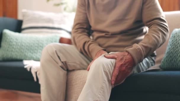 家のクローズアップのリビングルームのソファーの上のシニアの人との手 膝の痛みまたは骨粗しょう症 マッサージ 脚または解剖学および関節傷害 線維筋痛または炎症を有する高齢者 — ストック動画