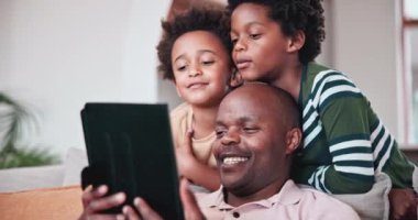 Siyah aile, video görüşmesi için tablet ve çocuklarıyla birlikte evlerinin oturma odasındaki kanepede oturan bir baba. Gülümse, sanal sohbet et ya da bir çocukla, kardeşiyle ve babasıyla evlerinde uygula..