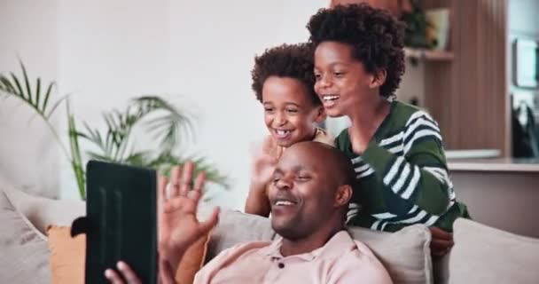 ブラックファミリー ビデオ通話用のタブレット 子供と一緒に自宅のリビングルームのソファーにいる父親 スマイル または彼らのアパートで男の子 父親と一緒に挨拶 — ストック動画