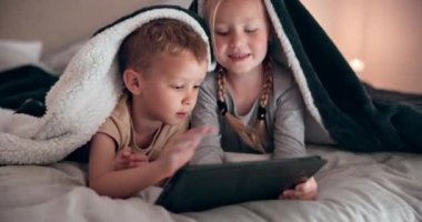 Gülümseyin, tablet ve çocuklar yatakta battaniyeyle rahatlayın, kaynaşın ve internetten para kazanın. Mutlu, dijital teknoloji ve çocuklar hafta sonları yatak odasında oyun oynuyorlar.