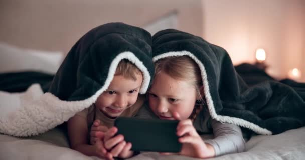 ハッピーな子供たち または電話 デジタルゲーム またはベッドで結合のための愛のケア ベッドルームで会話でオンライン漫画 テクノロジー ストリーミングビデオを視聴するガール 男の子 スマートフォン — ストック動画