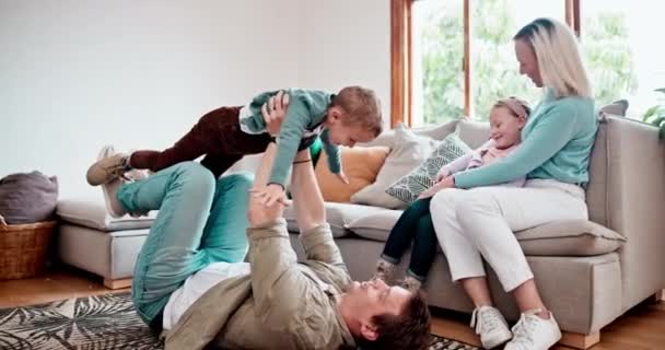 ハッピー 子供たちと一緒に現代の家でリビングルームのソファーで両親と一緒に 家族の家でラウンジで飛行機のための母親と父親とのスマイル 遊び心のある子供たち — ストック動画