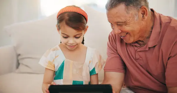 Home, grandfather and girl with tablet, smile and relax with social media, online gaming and digital app. Apartment, elderly man and pensioner with grandchild, tech and happiness with fun or network.
