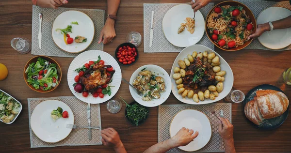 Family home, top view and food on table with hands, plate and dish for festive celebration. Vegetables, bread and chicken in dining room, house and people together for social holiday brunch at event.