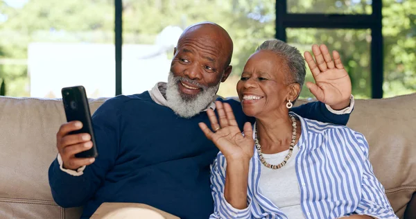 Happy senior couple, video call and smartphone in home for voip communication, social network or chat. African man, woman and wave hello for virtual conversation, mobile contact or talk in retirement.