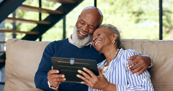 Tablet, hug and senior couple on a sofa for web communication, network or chat at home. Digital, app and old people embrace in living room with love, social media or streaming subscription in a house.
