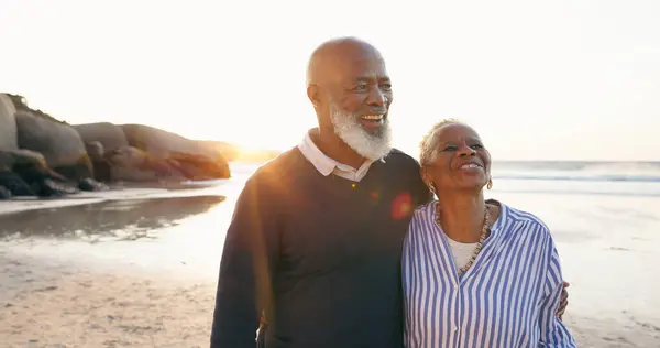 Senior couple, smile and hug by ocean, love and bonding on vacation, holiday and trip to beach. Happy black people, embrace and support or trust, commitment and connection in marriage or retirement.