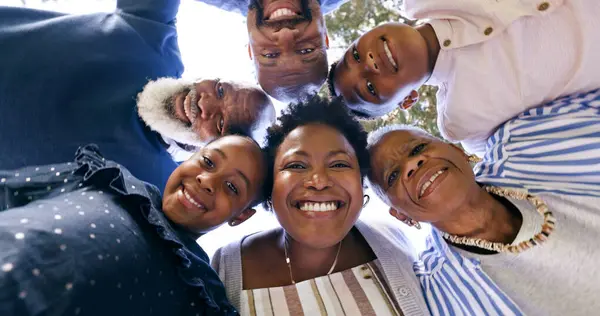 Happy, huddle or portrait of a black family in nature for fun bonding or playing in a park together. Smile, support or below of mother with grandparents, father or children to hug or relax on holiday.