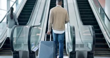 Seyahat, yürüyen merdiven ve havaalanında bavullu bir adamın ya da bir terminalde tatil gezisinin arka görüntüsü. Uluslararası bir yolculukta bavul, seyahat ve göçmenlik.