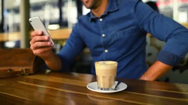 Kafe 'de sosyal medya veya iletişim için yakın çekim yapan biriyle el, telefon ve kahve. Cep telefonu, iletişim ya da ağ kurmak ve rahatlamak için kafein içeceği olan bir restoranda bir müşteri.