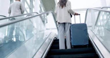 Havaalanı, bavul ve uluslararası seyahat veya ulaşım için yürüyen merdivende çalışan bir iş adamının arkası. Terminaldeki kurumsal, küresel ve profesyonel insanlar, seyahate ya da seyahate çıkıyorlar.