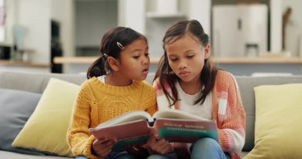 姐妹和在沙发上读一本书 了解家里的知识和家里的幻想 孩子们 学习和躺在沙发上 用笑声或爱心讲述知识或故事 — 图库视频影像