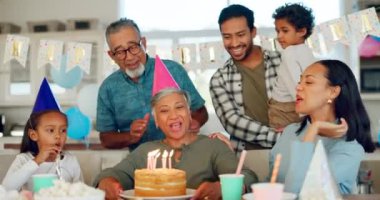 Doğum günü, parti ve ailesiyle birlikte bir hayat dönüm noktasını kutlamak için yaşlı bir kadın. Çocuklar, ebeveynler ve büyükanne ve büyükbabalar bir evde son sınıf öğrencilerini kutlamak için pasta yiyorlar..