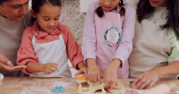 家庭用キッチンカウンターで焼くことを学ぶおばあちゃん お母さん そして子供たちは スキルやケアとしてデザートを準備します 少女がクッキーのレシピや食べ物で子供たちを教えたり助けたりする — ストック動画