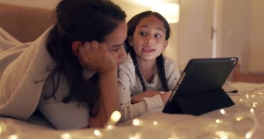 Tablet, bed or mother with child streaming a movie as a family to relax at night at home on weekend. Parent, mom or girl watching film, series online or social media together on technology in bedroom.