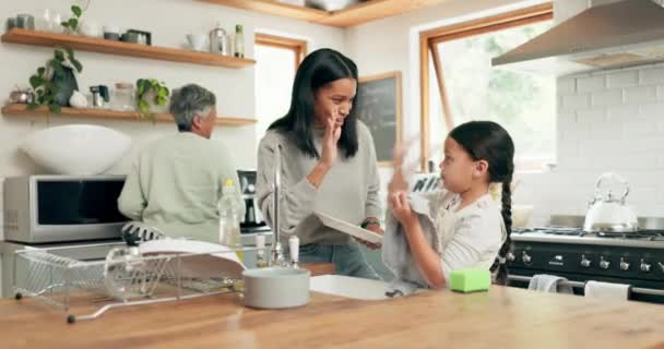 子供はおばあちゃんとお母さんと一緒に台所を掃除しながら 笑っています 幸せな笑顔と女の子子供洗浄皿とともに彼女の若いお母さんとシニア女性で彼らの家族の家 — ストック動画