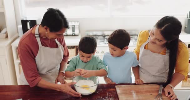 家庭で家庭料理のレシピを学ぶキッチンでお母さんと一緒に焼くおばあちゃん 卵や子供 開発または誇りに思って祖母はクッキーのペストリーのための小麦粉ボウルで子供たちを支援または教える — ストック動画