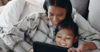 Anne, kız ve çocuk yatak odasında online oyunlar için tabletle kitap okuyorlar ve medyayla rahatlamak için gülümsüyorlar. Kadın, anne ve mutlu çocuk evde çizgi film, film ve dijital teknoloji yayınlıyorlar..
