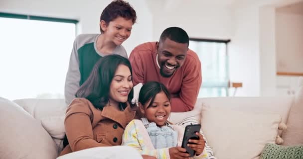 快乐的孩子们 带着父母坐在沙发上的电话和孩子们住在现代家庭的客厅里 在休息厅与跨种族的父母一起在手机上看视频 开心而年轻的孩子们都在笑 — 图库视频影像