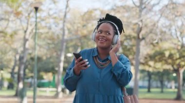 Afrikalı iş kadını, kulaklıklar, açık havada dans, parkta müzik, gülümseme, hareket ve yaz. Siyahi girişimci, akıllı telefon ve ses teknolojisi ile doğada dans ile ses yayını hizmeti.