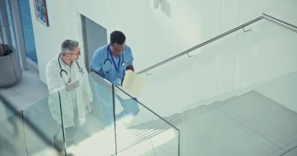 医生和护士带着医院大厅里的文件走在楼梯上 进行对话 医疗专业人员或外科医生 讨论在诊所采取的步骤 提供医疗 团队合作或协作方面的文件服务 — 图库视频影像