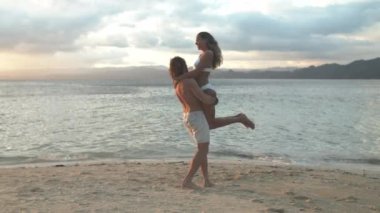 Mutlu çift, sahilde sarılıp oynuyorlar aşk için rahatlıyorlar, bağlanıyorlar ya da okyanus kıyısında tatilin tadını çıkarıyorlar. Kadını deniz kıyısında kucaklamak, ilgilenmek ya da dışarıda romantizm yaşamak için doğada birlikte taşıyan bir adam..