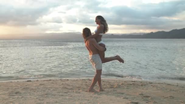 一对快乐的夫妇 在海滩上拥抱和玩耍 放松地谈情说爱 谈情说爱 或享受海滨度假 男人把女人抱在海里 在大自然中拥抱 呵护或在户外谈情说爱 — 图库视频影像