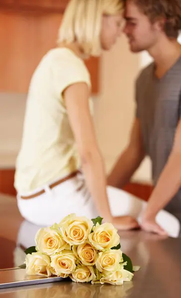 Couple, flowers and hug in kitchen love for anniversary celebration, connection or romantic date bonding. Woman, man and partnership in home with roses for surprise bouquet, present for floral gift.
