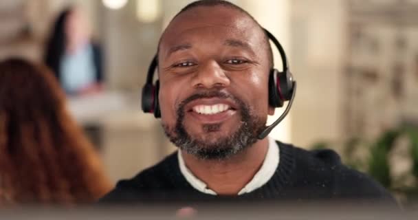呼叫中心和一个黑人男人说话与耳机客户服务 建议或Crm 在服务台为电信 电话推销或技术支持工作到很晚的快乐的人 — 图库视频影像