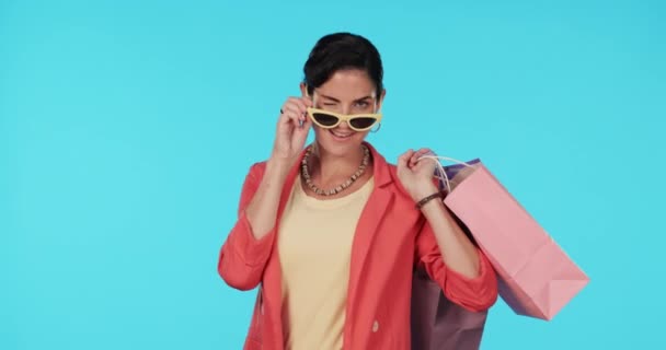 太阳镜 购物袋或快乐的女人在工作室的蓝色背景与凉爽的衣服 微笑或富有的女孩 带着礼物或产品接受折扣或促销 — 图库视频影像