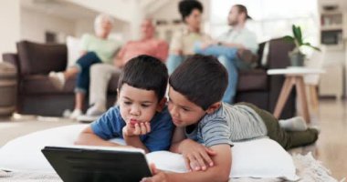 Ev, tablet ve rahatla aile çocukları video, abonelik filmi ya da çizgi film, medya ya da web uygulaması izliyor. Oyun arkadaşları, kardeşler ve çocuklar online oyunlar oynuyorlar, kaynaşıyorlar ve yerde yatıyorlar..