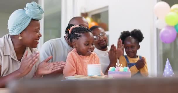 誕生日 子供たちと彼らの家の女の子の子供を祝うために黒の家族とキャンドルを吹くためのパーティー マイルストーンイベントでケーキの周りに拍手で拍手をしている両親 祖父母 — ストック動画