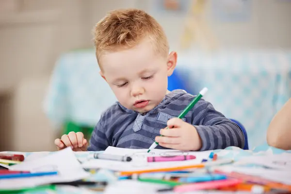 Face, kid and pencil for drawing in classroom for learning, education and development of motor skills. Little boy, student or learner with coloring activity for growth, future or milestone in daycare.