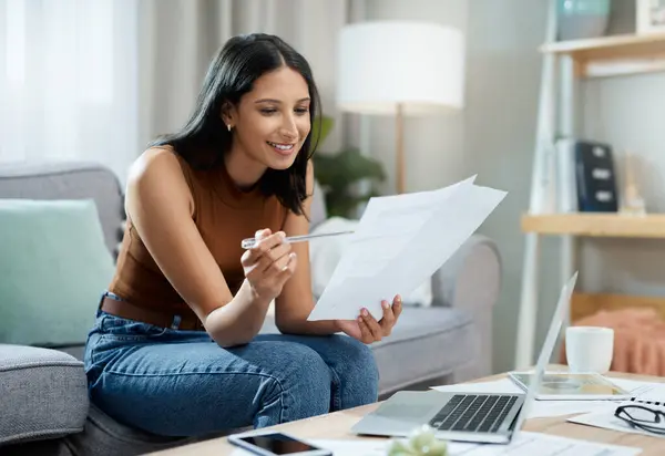 stock image Happy woman, laptop and documents on sofa for finance, expenses or paying bills in living room at home. Female person smile with paperwork for good budget, investments or financial plan at house.