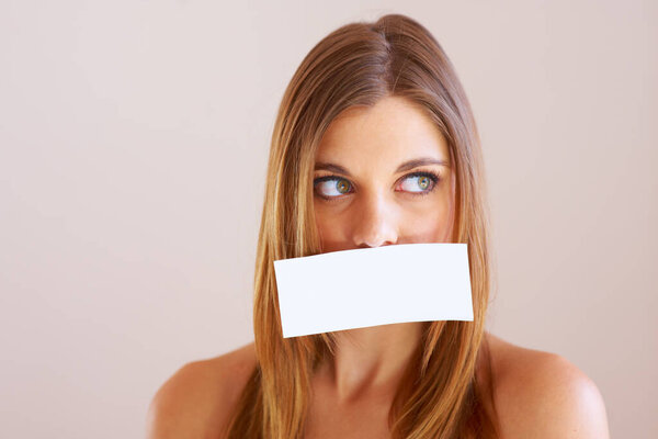 Woman, looking and cover for mouth with mock up for silence in studio on white background. Female model, face and placard for talking, shh or quiet with copy space for announcement, secret or gossip.