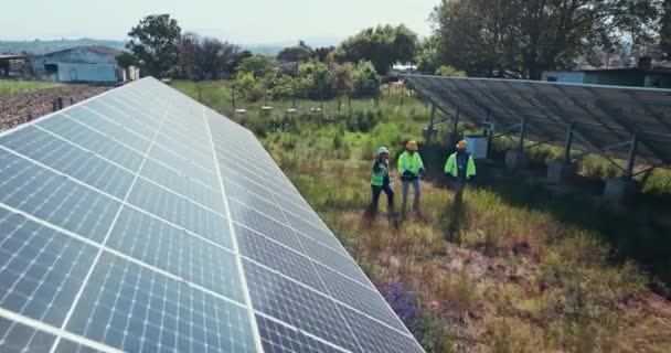 クリーンエネルギーおよび屋外の電力網の維持のための太陽電池パネルの植物で歩いている人々 サステナビリティ 太陽光発電 そして電気農場で再生可能なシステムと話し合う男性 — ストック動画