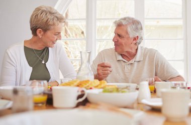 Kahvaltı, sohbet ve yaşlı bir çiftle öğle yemeği, bir evde birlikte yemek ve mutlu olmak. Sevgi, destek ve özen ile bir yemek odasında gülümseme ve yemek ile sabah evde meyve ile bağlanma.