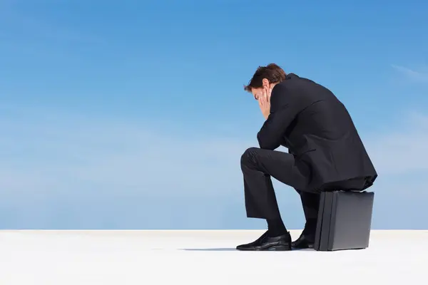 Depression, sky and business man sad, burnout or stress over corporate mistake, company disaster or agency fail. Mental health risk, mockup space and back of professional person sitting on briefcase.