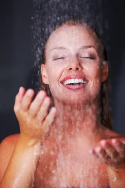 Shower, woman and water drops in studio for relax, healthy skincare or wellness with peace in mockup. Young model, happy and natural glow of cleaning body and self care for beauty by black background.
