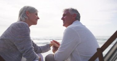 Kıdemli çift, mutlu ve kumsalda el ele tutuşuyorlar ve evlilik kucaklaşmayla, tatille ve emeklilikle. Emeklilik, yaşlılık ya da bağlılık sevgisi, bağlanma ve romantik ilişki için bakım.